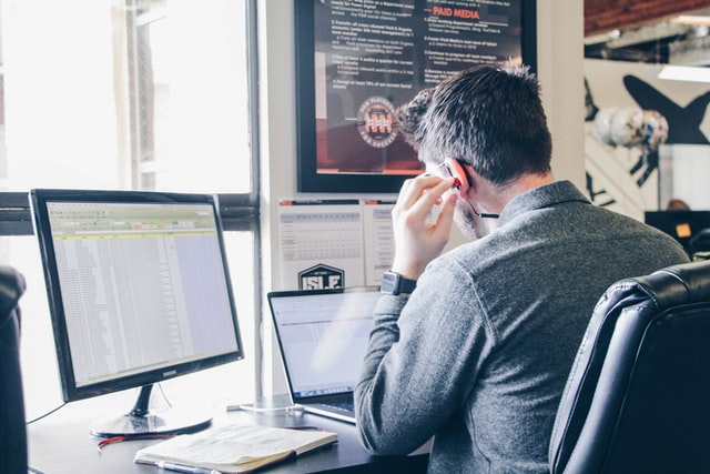 Man with earpods and 2 screens