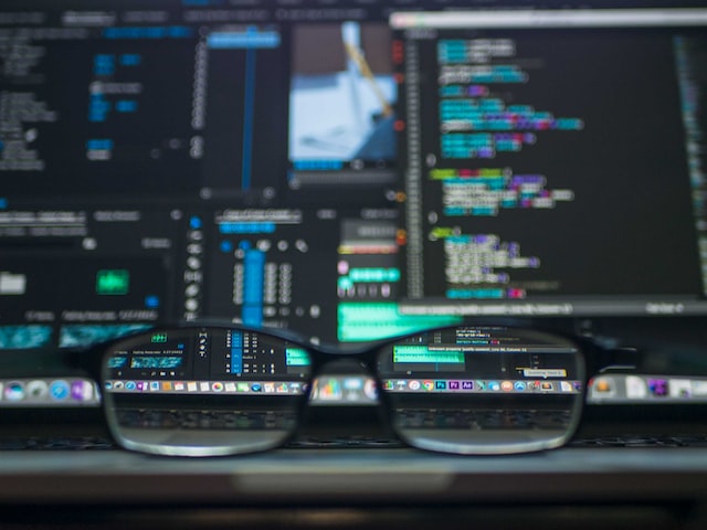 Screens of code with a pair of glasses in the foreground